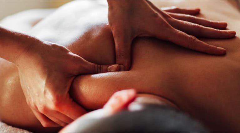 Someone laid down, receiving a shoulder massage