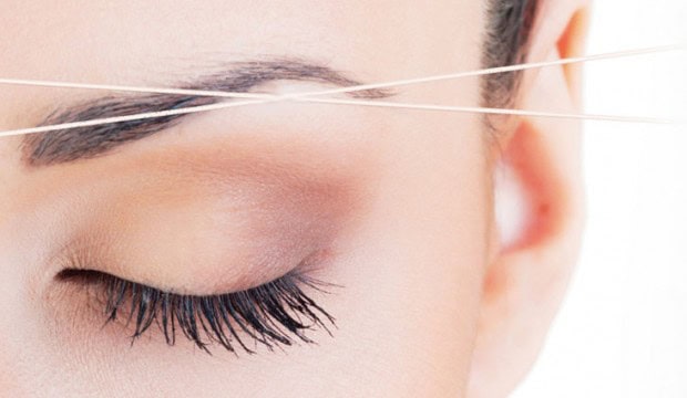 A woman receiving an eyebrow shaping (threading) treatment