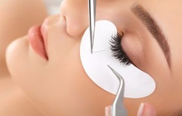 A woman receiving eyelash extension treatment