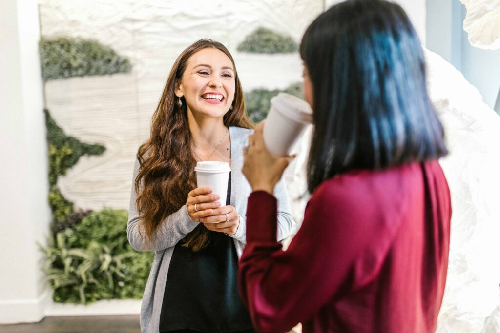 Two women laughing whilst drinking coffee